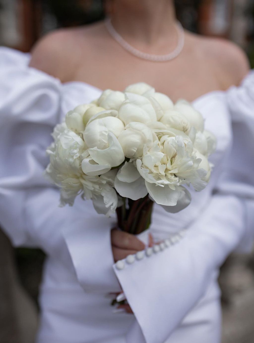 A bride holding a white peony bouquet